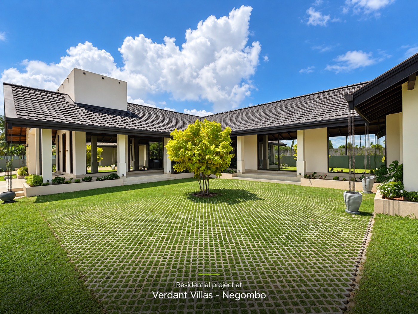 The central courtyard lawn with grass pavers and a single tree, framed by the three wings of the house