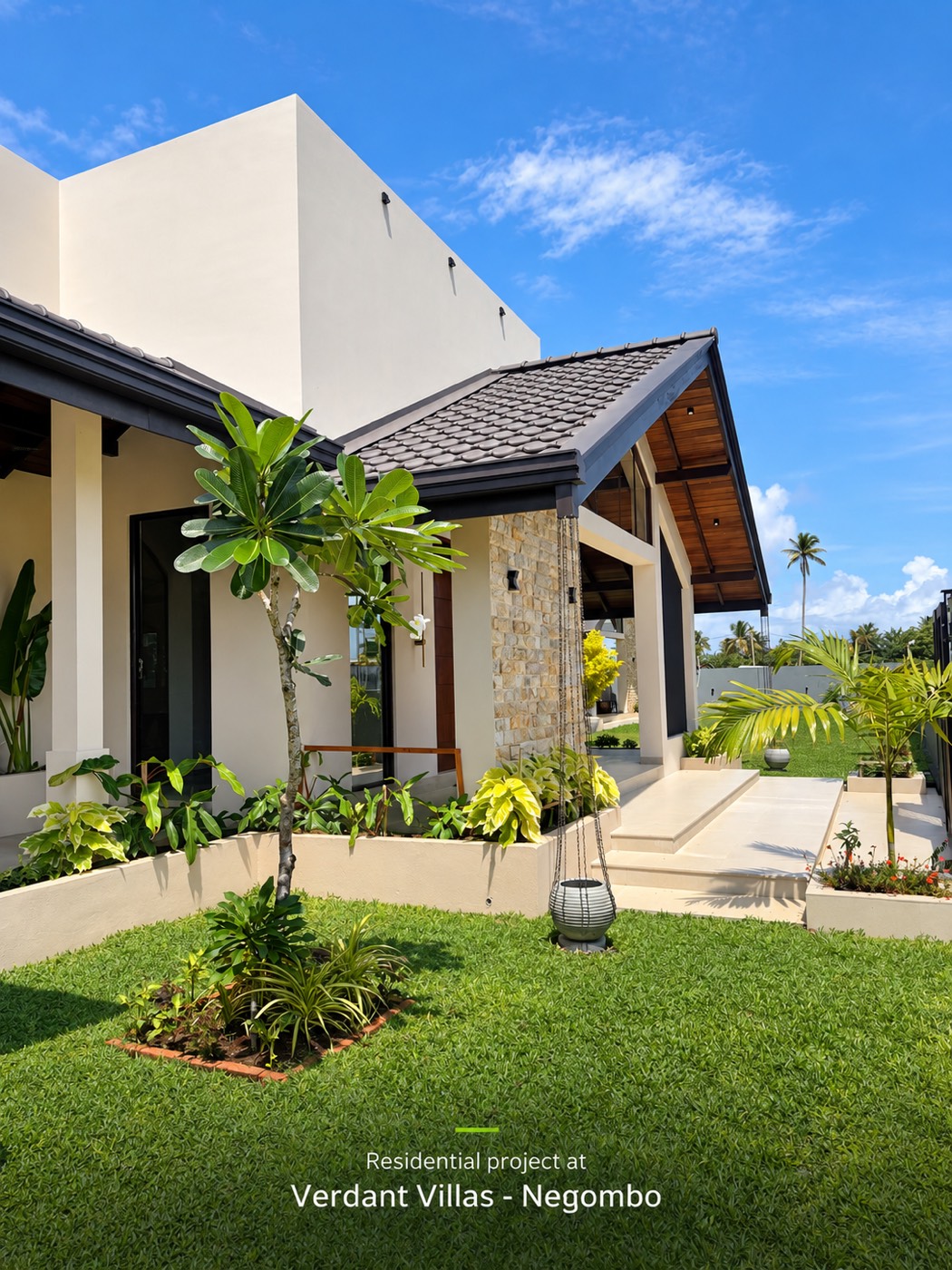 The entrance corner with the stone-clad wall, the tall white box and a frangipani tree